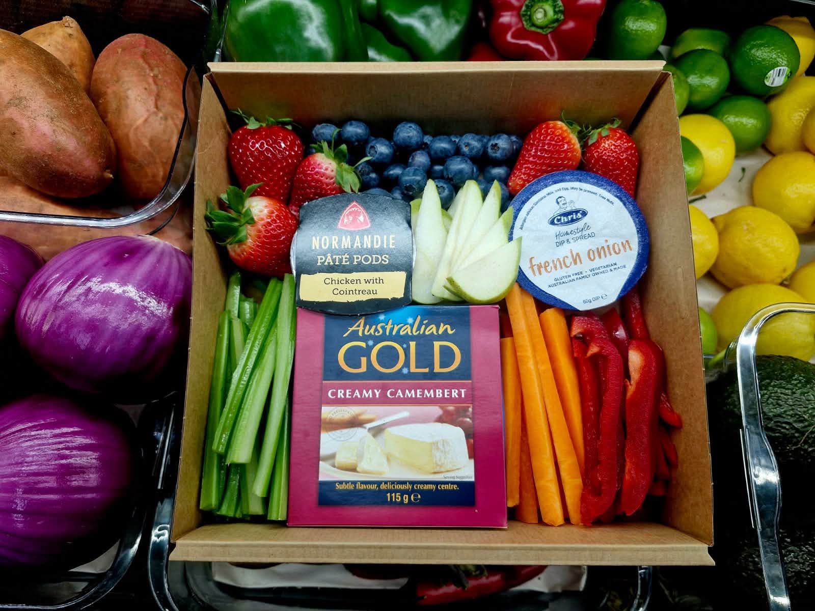 Strawberries, blueberries, pear slices, carrot, celery and capsicum sticks in a cardboard box